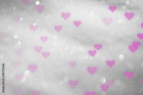 Pink colored hearts on blurry silver bokeh background.