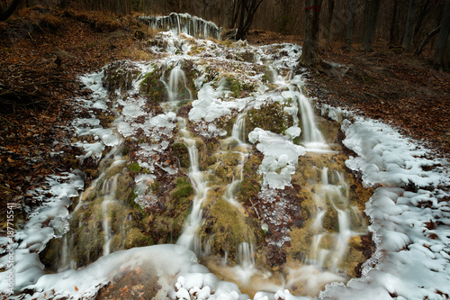 Frozen wild waterfall in the mountains photo