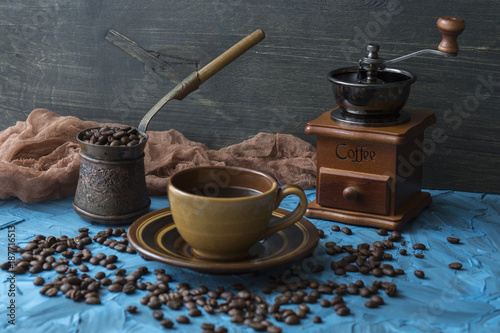 on a blue background a cup of coffee, turka, coffee beans and a coffee mill