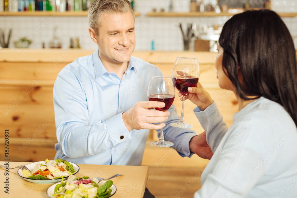 Tastying wine. Good-looking inspired well-built man and a dark-haired woman sitting together and drinking wine and having dinner
