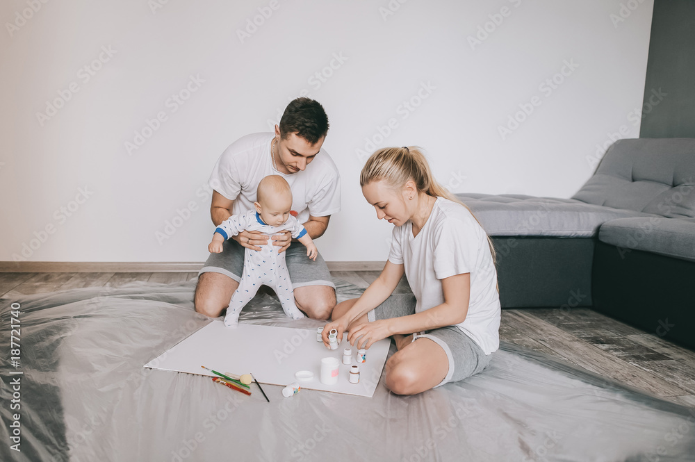 happy young family with beautiful little infant child painting together on floor at home