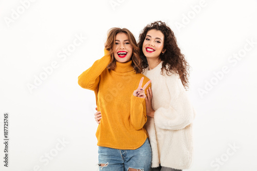 Two smiling girls in sweaters posing together