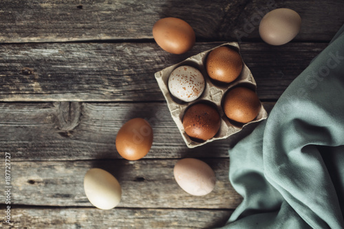 Brown eggs and kitchen towel on an old wooden table, top view