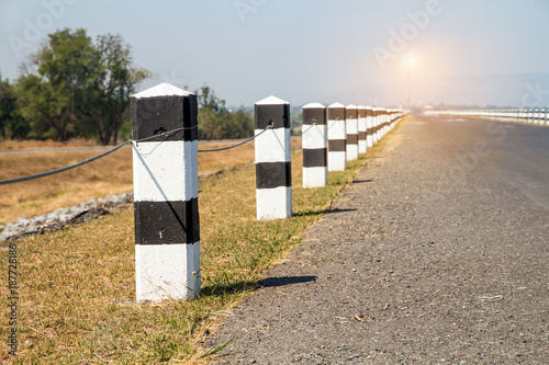 Milestones,black and white milestones with green grass roadside,lake roadside in background,concept for next step.go on
