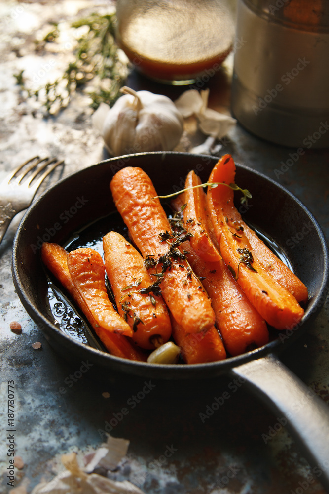 Baked carrots with heavy frying pan on rustic background Baked carrots with heavy frying pan on rustic background