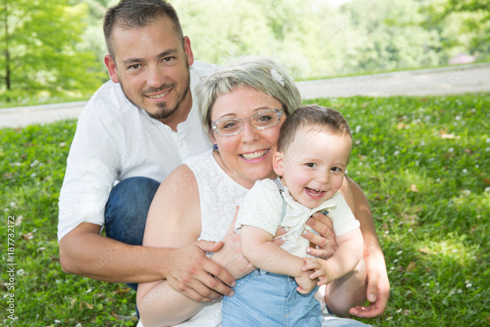 happy mother and father hugging his little son in park happy mother and father hugging his little son in park