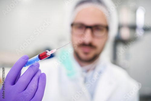Close up of a doctors hand holding syringe with blood. Analyzing blood in the laboratory.