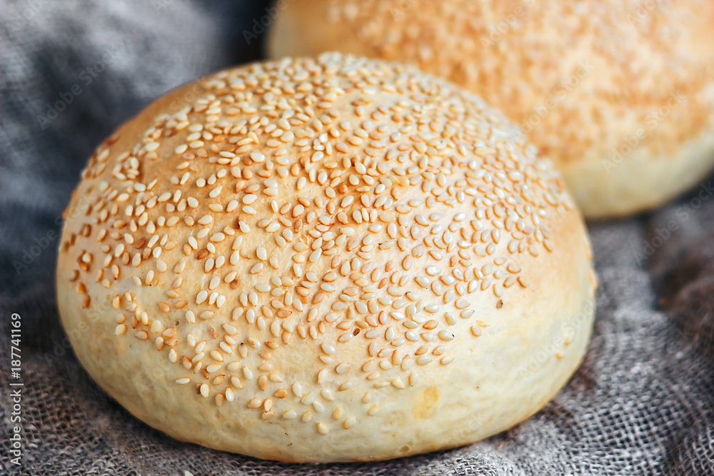 Round bun, sesame bun, bread rolls. Tasty burger bread with sesame on wooden, burlap background. Freshly baked hamburger buns. Top view. Round bun, sesame bun, bread rolls. Tasty burger bread with sesame on wooden, burlap background. Freshly baked hamburger buns. Top view.