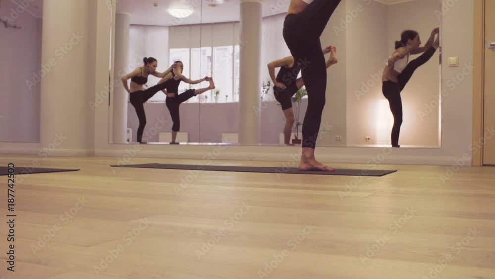 Yoga class. People practicing yoga in bright studio. Ashtanga yoga. Extended hand-to-big-toe pose Yoga class. People practicing yoga in bright studio. Ashtanga yoga. Extended hand-to-big-toe pose