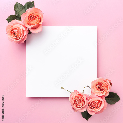Blank paper note and roses on pink background