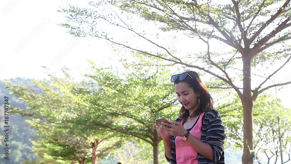 Happy Young Woman Using Smartphone Chat to Friend in the Park Happy Young Woman Using Smartphone Chat to Friend in the Park