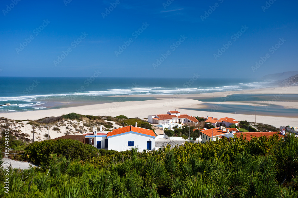 oast of the Atlantic Ocean in Portugal. waves, white sand. small house with a red roof, the city of Obidos
