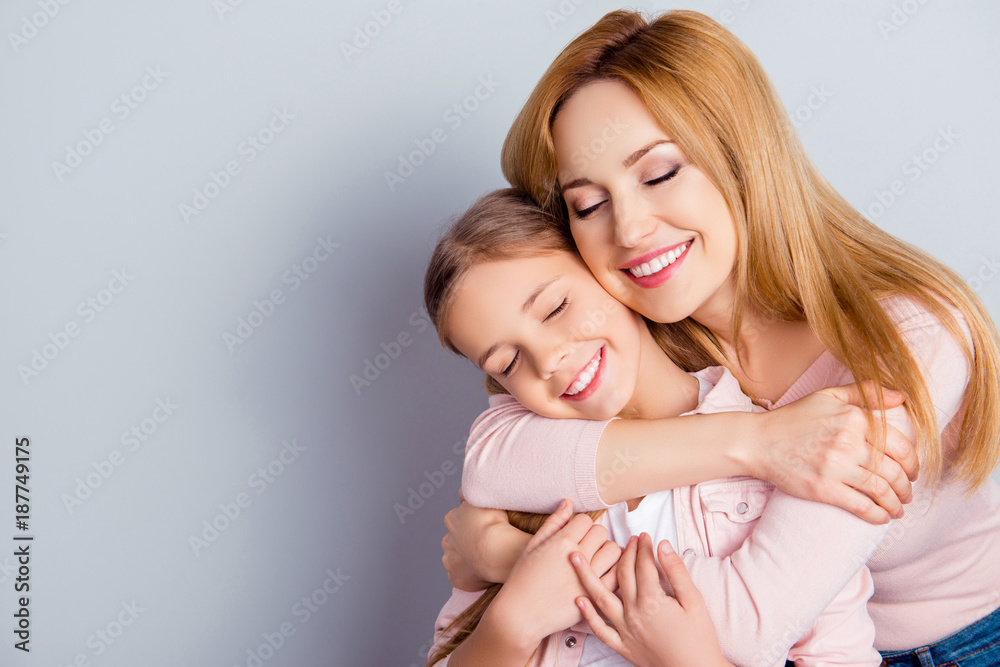Portrait with copyspace of pretty, lovely mother and daughter embracing over gray background with close eyes, weekend, leisure, happiness, fun, leisure, relatives