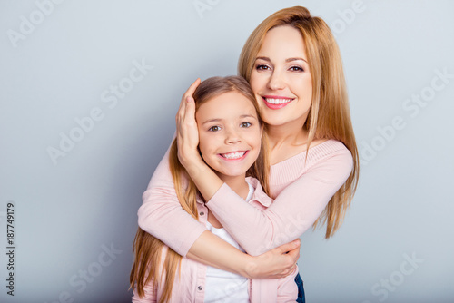 Pretty, lovely mother and daughter embracing over gray background, looking at camera, leisure, weekend, happiness, fun, leisure, relatives