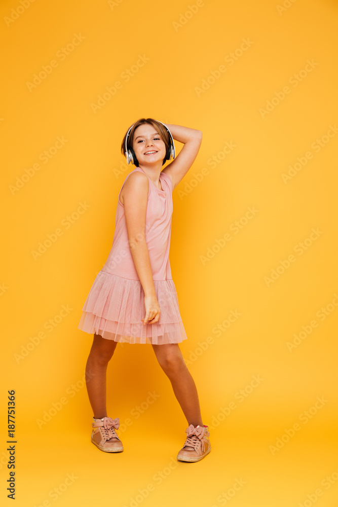Funny smiling girl in headphones posing isolated over yellow Funny smiling girl in headphones posing isolated over yellow