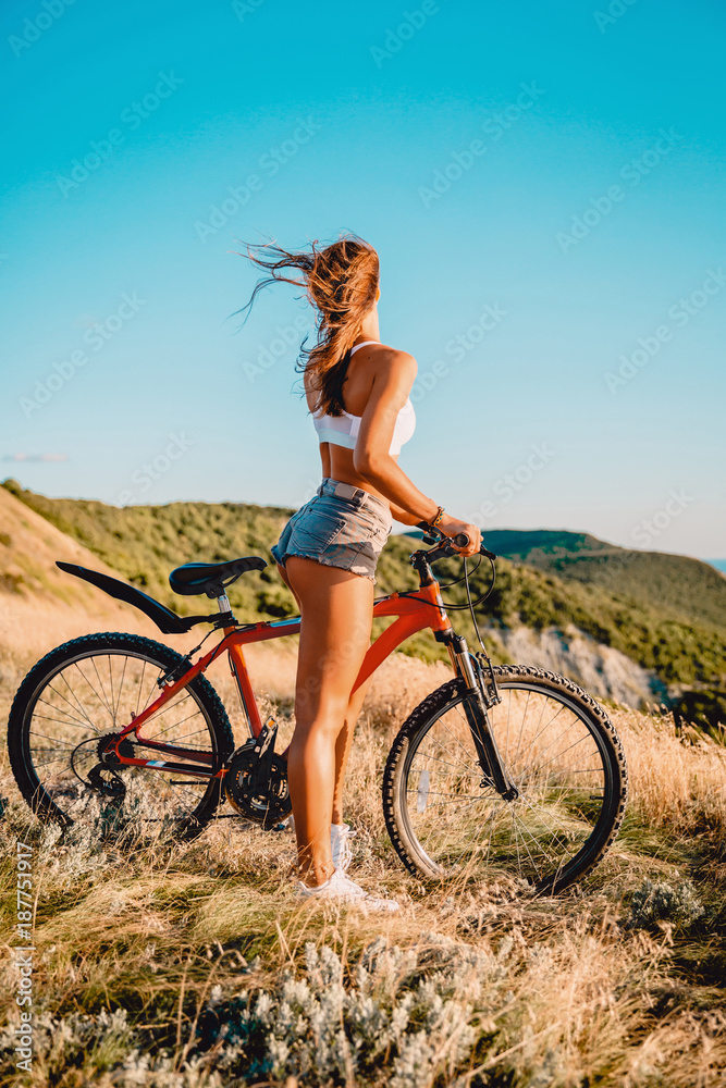 Young active girl with mountain bicycle in white shirt, shorts and white sneakers outdoor Young active girl with mountain bicycle in white shirt, shorts and white sneakers outdoor