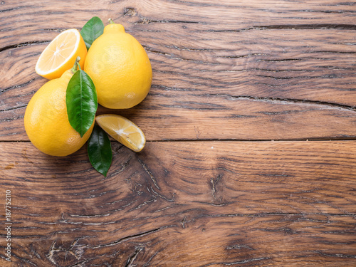 Ripe lemons and lemon leaves on wooden background. Top view.