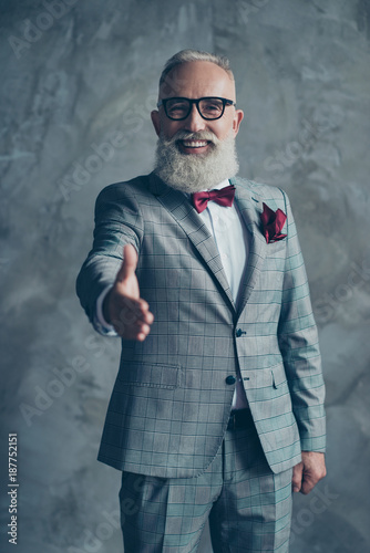 Cooperating people concept. Hello! Vertical portrait  excited confident freelancer wearing stylish trendy checkered grey classic suit, maroon accessories giving hand to you isolated on gray background