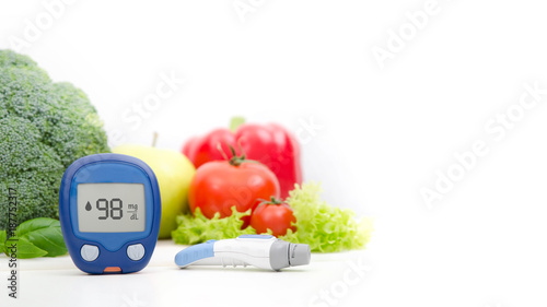 Glucometer and lancelet on vegetables background