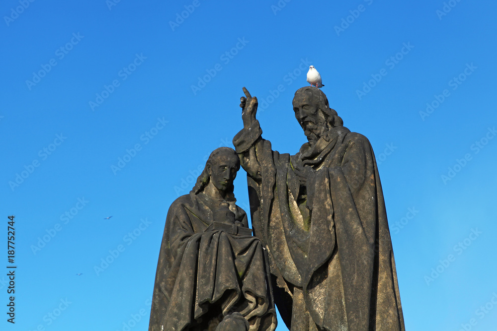 Fototapeta premium Pigeon sitting on sculpture's head on Charles Bridge, Prague, Czech Republic