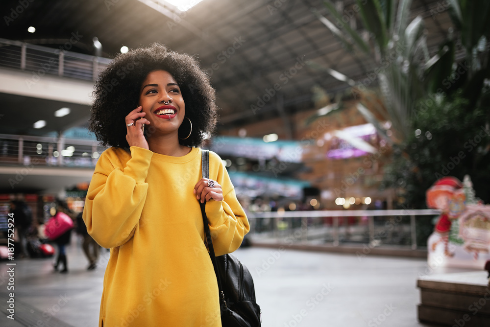 Fototapeta premium Beautiful afro woman using mobile in the train station.