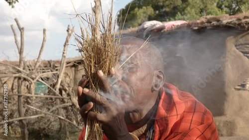 a maasai warrior starts a fire the traditional way without matches at a manyatta in kenya photo