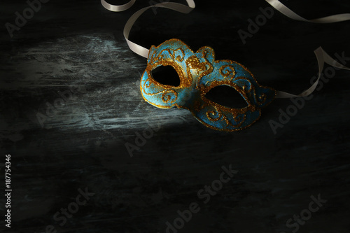 Image of elegant blue and gold venetian, mardi gras mask over black background.