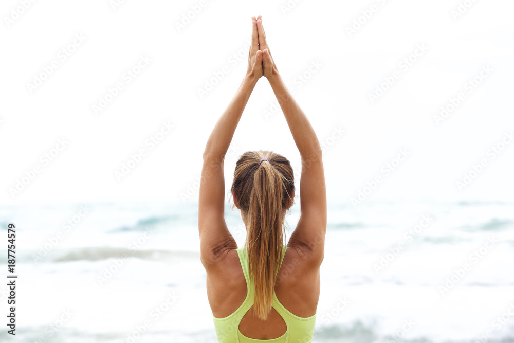 yoga woman with hands up by the sea