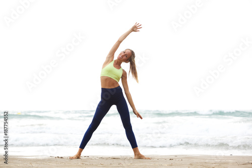 Full body happy yoga woman stretching at the beach