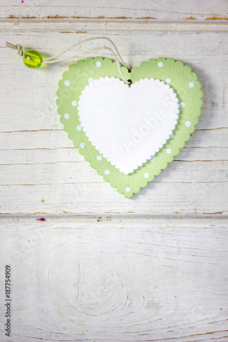 Two wooden hearts - white and green over the wooden background