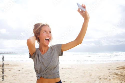 PHappy young woman taking selfie with cell phone at the beach photo