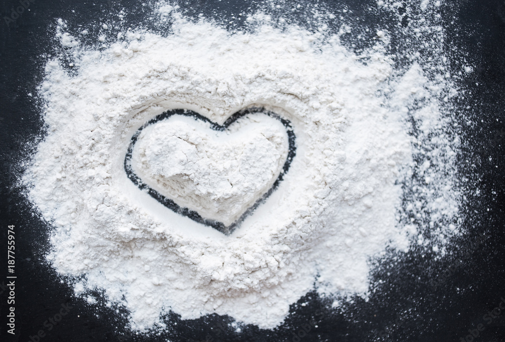 Fototapeta Valentine Day Concept idea image - Heart shape in a baking flour on black background. Cooking love recipe concept