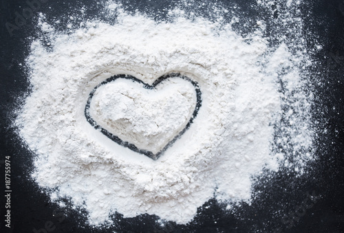 Fototapeta Valentine Day Concept idea image - Heart shape in a baking flour on black background. Cooking love recipe concept