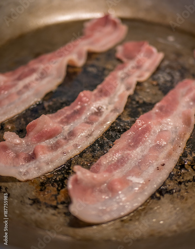 Frying bacon in steel pan.
