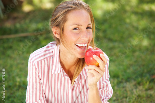 attractive young woman eating apple in the park