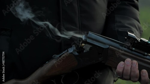 Impressive closeup shot of sportsman hands takes out a cartridge in a vertical double barrel shotgun outdoors. Slow motion. photo