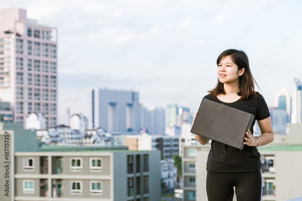 Sport asian women hold paper box stand on top of modern building Sport asian women hold paper box stand on top of modern building