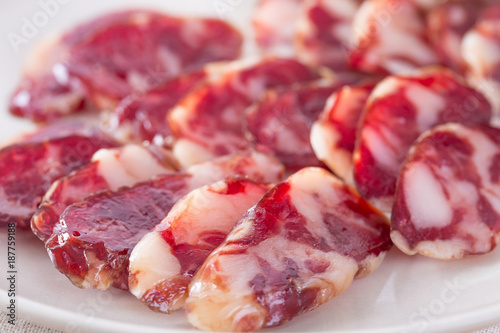 Close-up of cold cuts and vegetables on a plate. Raw pork sausage.