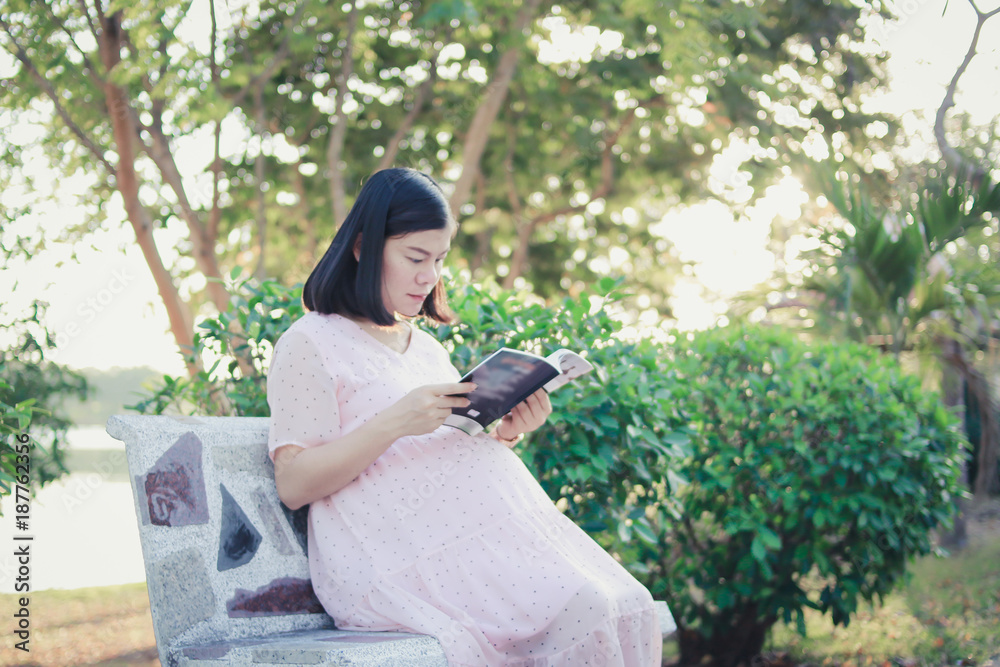 Fototapeta premium Pregnant woman sitting on a bench in park.