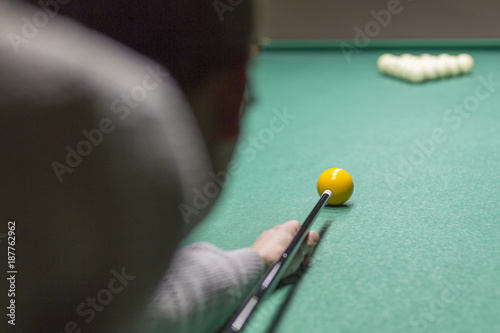 Billiards close-up on the green. Hands of a man holding a stick for playing billiards and aiming at the sharar on the table photo