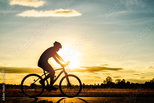 Silhouette man cycling at sunset