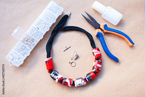 Assebly of handmade bright necklace red and black with pliers and tools.