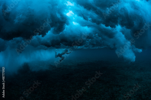 Fotografie Underwater view of the surfer diving under powerful ocean wave