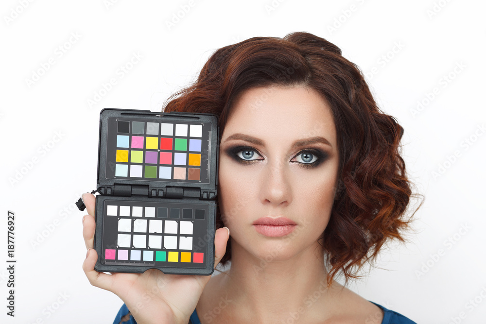 Close up beauty studio shot of beautiful redhead woman with gorgeous makeup curly hair holding color calibration target Close up beauty studio shot of beautiful redhead woman with gorgeous makeup curly hair holding color calibration target