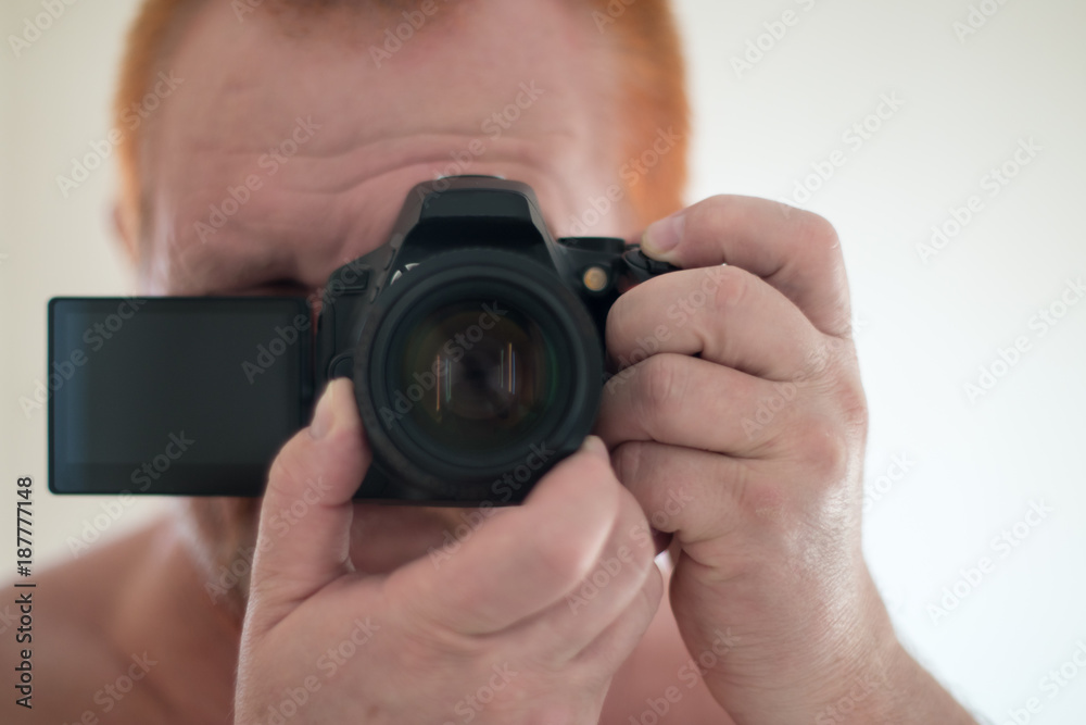 New camera with a folding touch screen using a mirror. Selective focus. Selfie, photograph that one has taken of oneself typically with smartphone and uploaded to a social media website. New camera with a folding touch screen using a mirror. Selective focus. Selfie, photograph that one has taken of oneself typically with smartphone and uploaded to a social media website.