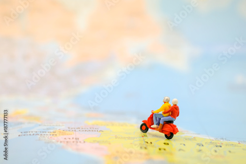 Travel Concept. Group of traveler miniature figures ride motorcycle / scooter on world map.