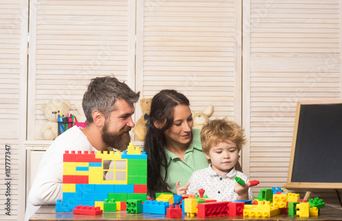 Father, mother and son in playroom on light wooden background.