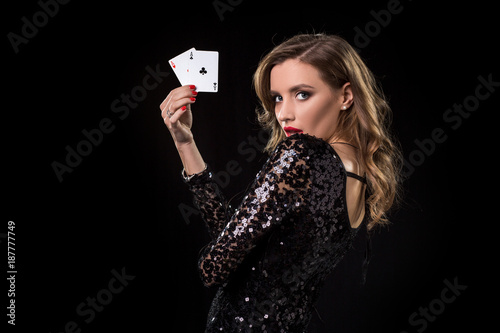 Young woman holding playing cards against a black background photo