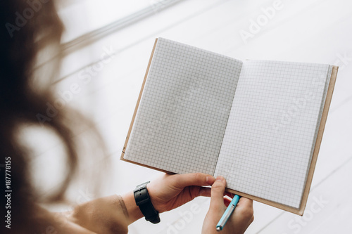 Notepad with space for text and a pen in the hands of a young girl. Top view photo