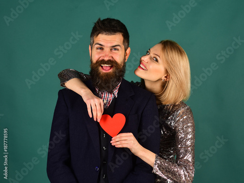 Girl and bearded man with happy faces play with heart.